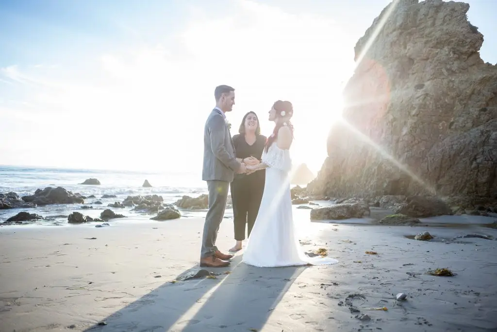 Beach elopement packages by Let's Get Married by Marie feature a Malibu Beach Elopement with a bride and groom saying their vows as the sun sets