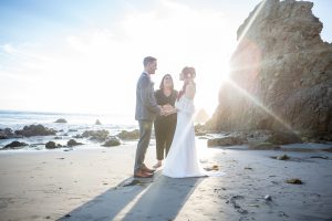 Los Angeles elopement packages by Let's Get Married by Marie feature a Malibu Beach Elopement with a bride and groom saying their vows as the sun sets