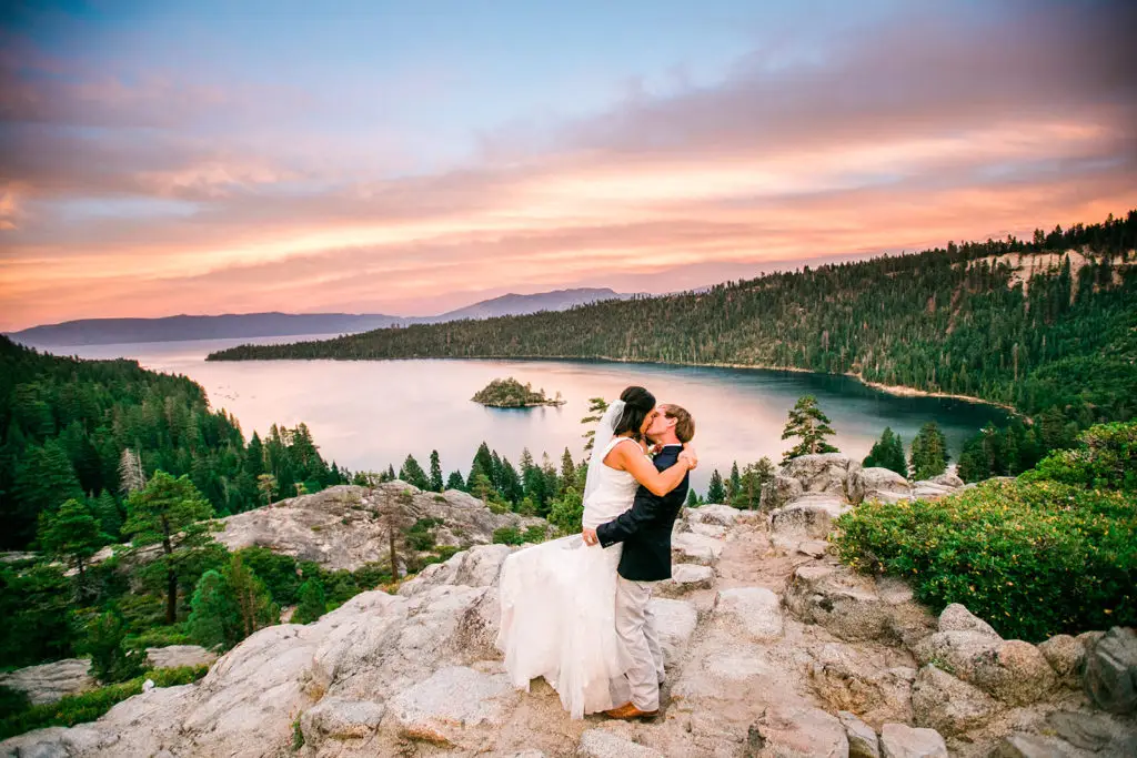 A newlywed couple kiss on the rocks overlooking Lake Tahoe during their Epic Elopement Experience with Let's Get Married by Marie