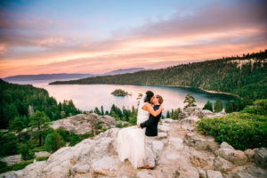 A newlywed couple kiss on the rocks overlooking Lake Tahoe during their Epic Elopement Experience with Let's Get Married by Marie