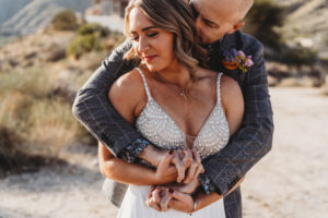 Palm Springs elopement packages by Let's Get Married by Marie featuring a groom with his arms wrapped aroudn his bride in the Palm Springs desert