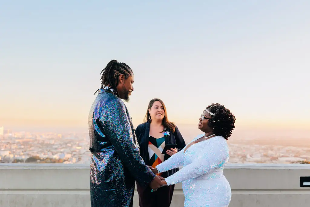 LA elopement packages with Let's Get Married by Marie feature a bride in a white dress and a groom in a sequined suit overlooking LA during their elopement ceremony with Minister Marie