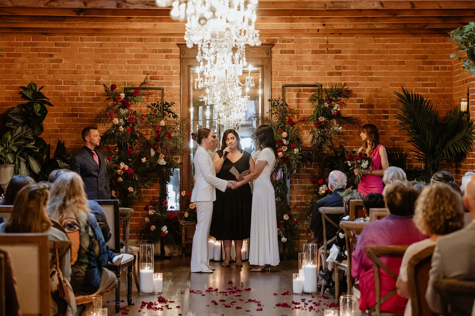 Let's Get Married by Marie performs a wedding for a bride in a white suit and a bride in a white dress at the Carondelet House