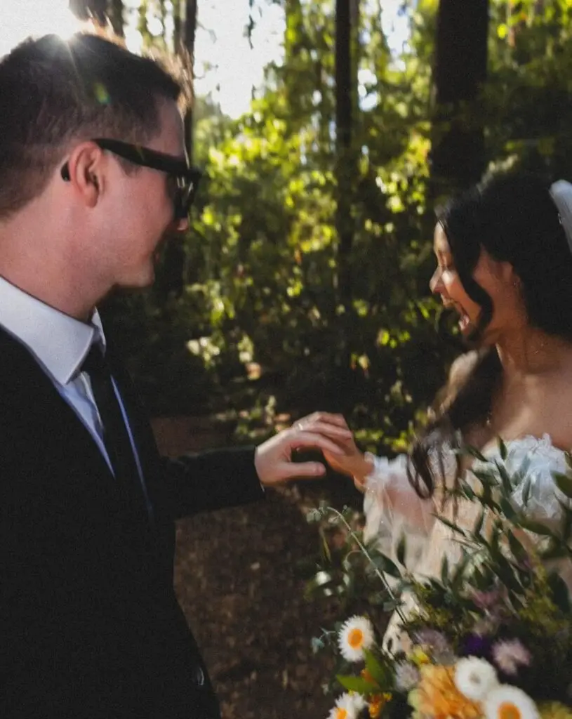 a bride laughs looking at her groom's new wedding band during their Redwoods elopement with Let's Get Married by Marie