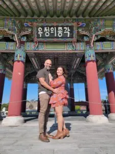 a couple hold each other in front of the Korean Friendship Bell after their vow renewal with Let's Get Married by Marie