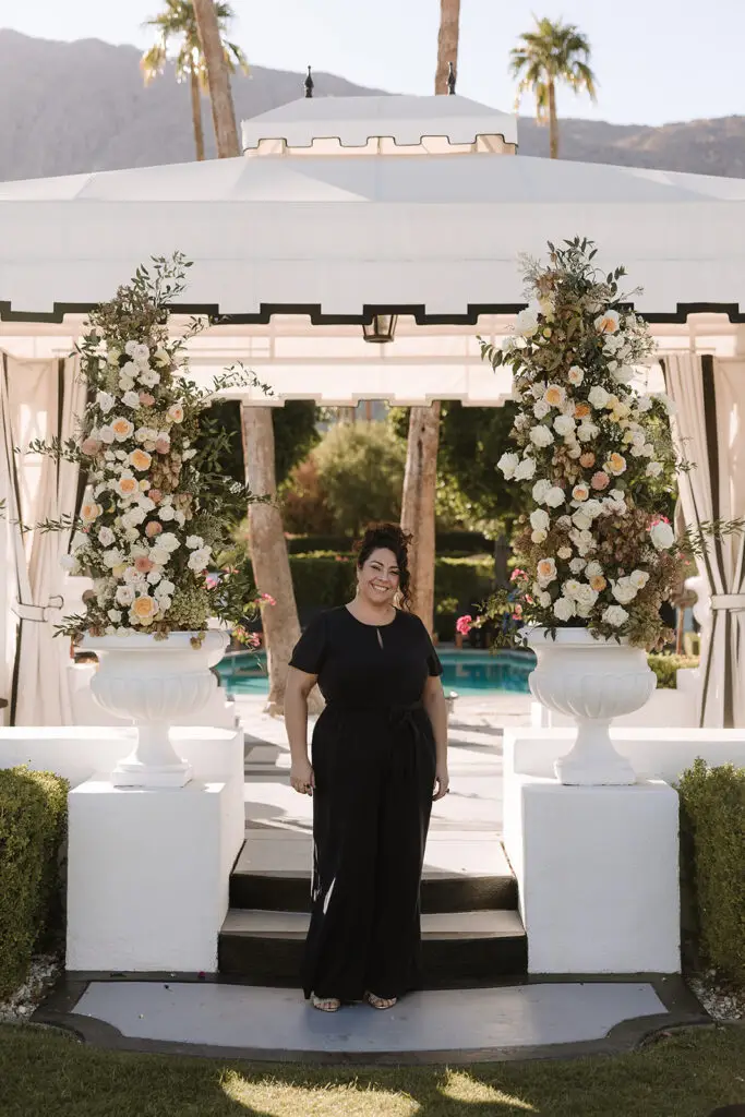 Minister Marie of Let's Get Married by Marie stands in a navy suit before a Palm Springs wedding