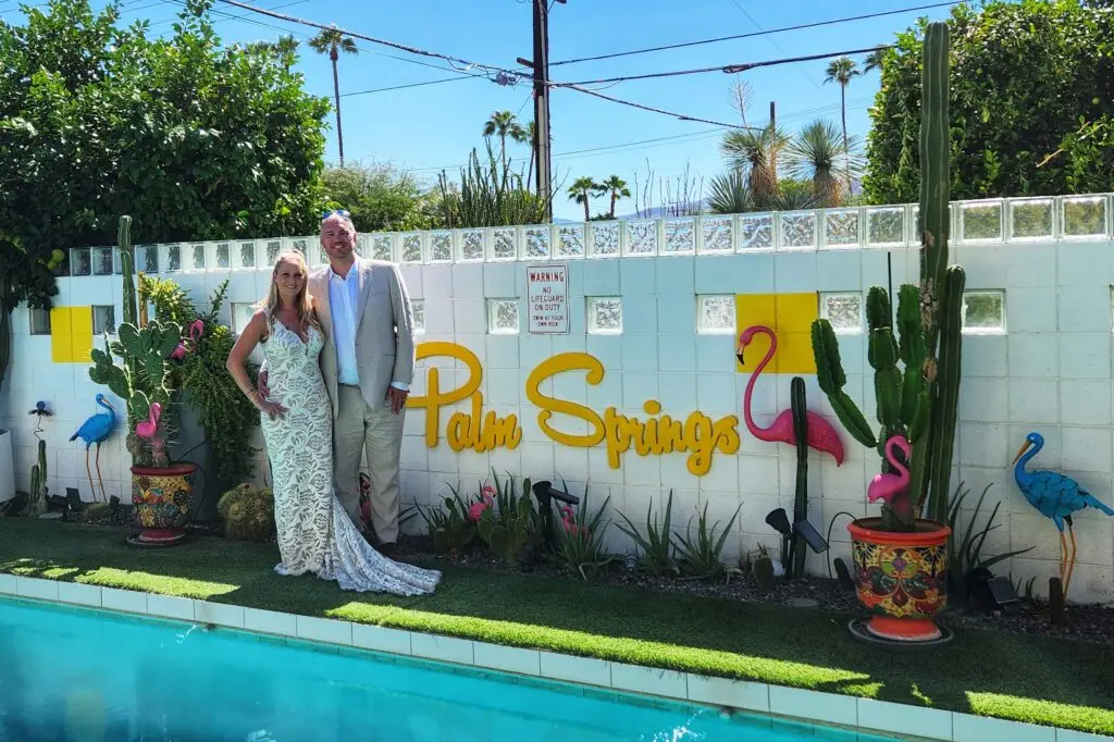 a bride and groom stand poolside after their intimate palm springs wedding with let's get married by marie